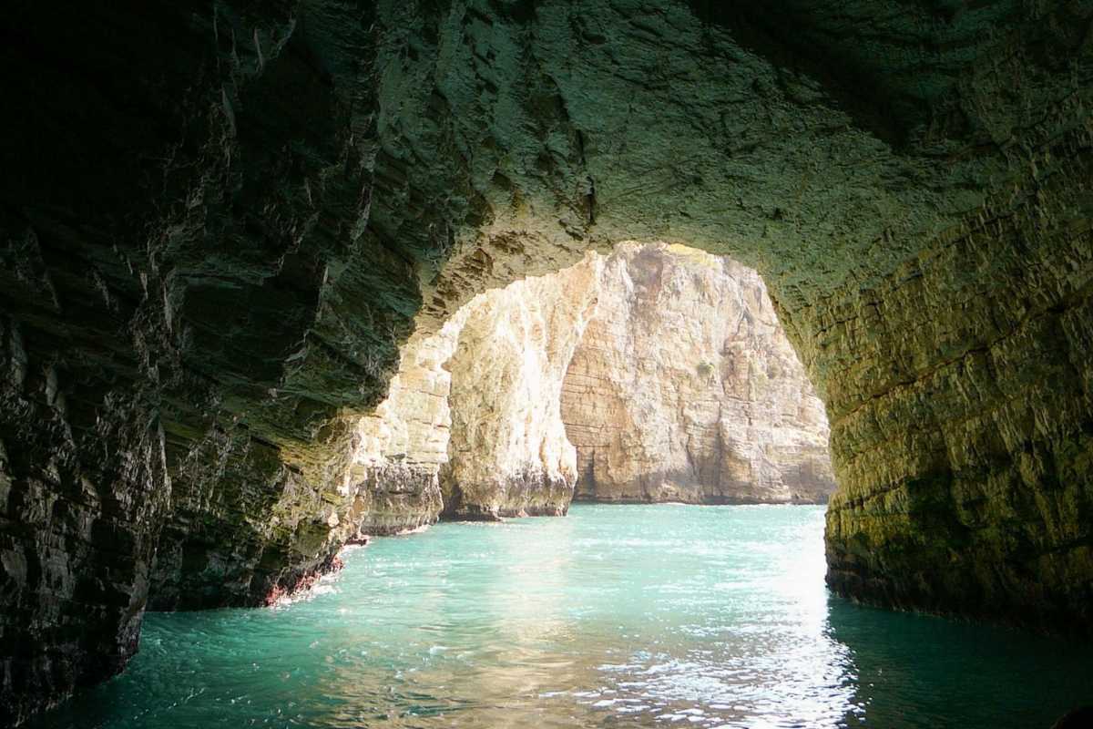 Spiaggia di Vieste al tramonto, con ombrelloni e sole che scompare all’orizzonte